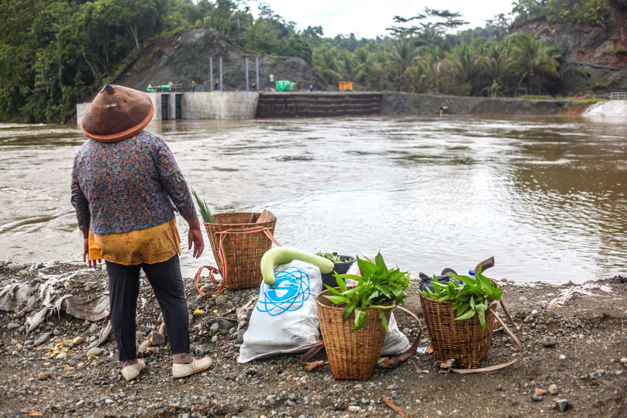 A woman from Kawasi standing on the banks of a river.