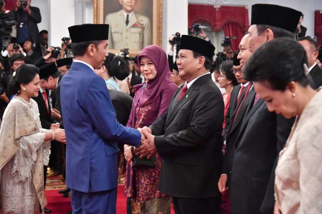 Joko Widodo shakes hands with Prabowo Subianto.