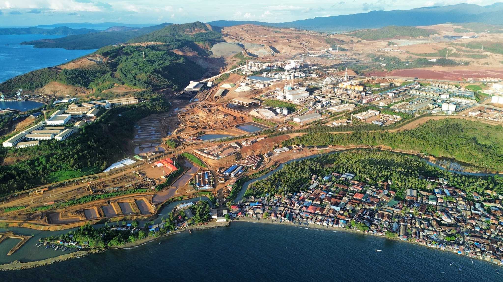 Aerial view of a coastal village with a large factory behind it
