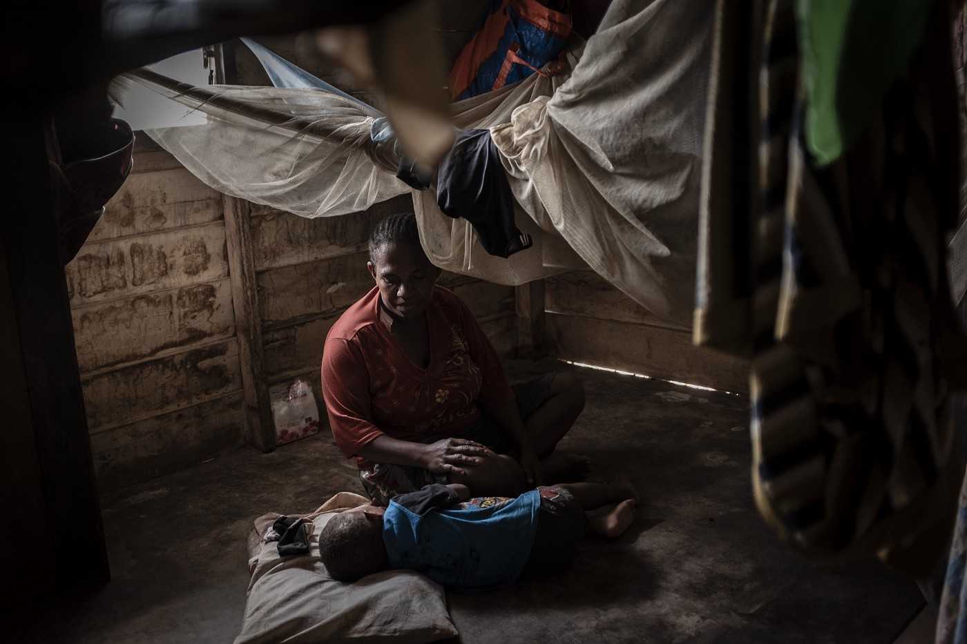 Angela, 29, tends to her youngest child at their home in Boven Digoel.